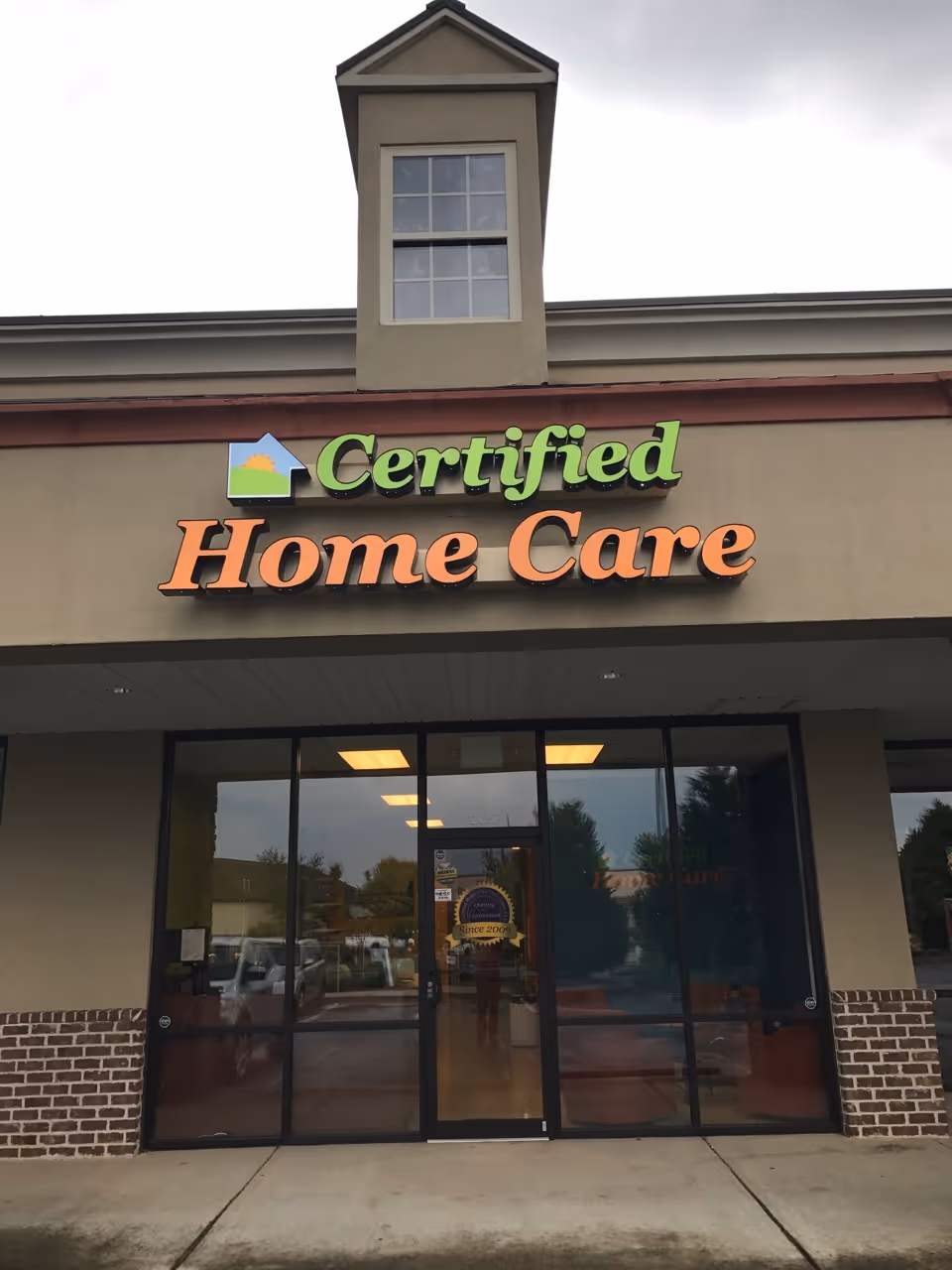 Front storefront of Certified Home Care facility with bold orange sign and glass doors.