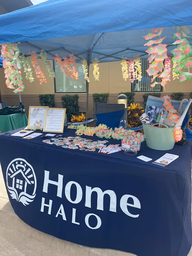 Outdoor booth for Home Halo with promotional materials under a blue canopy.