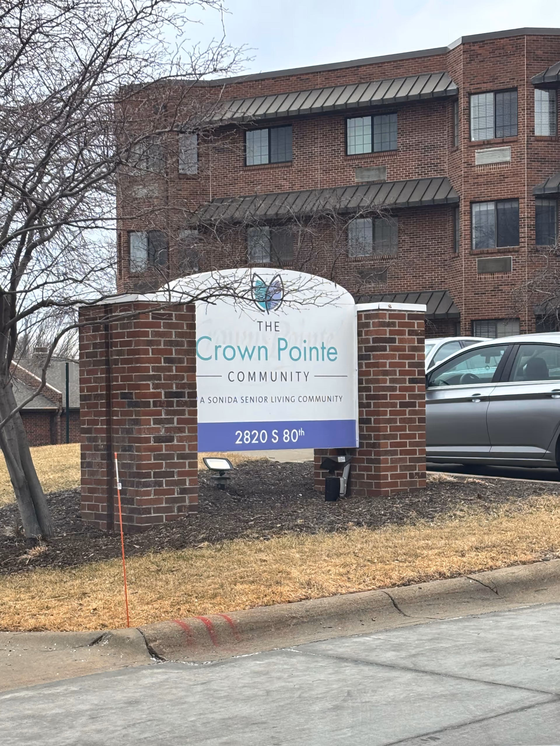 Brick senior living building with a front sign reading The Crown Pointe Community.