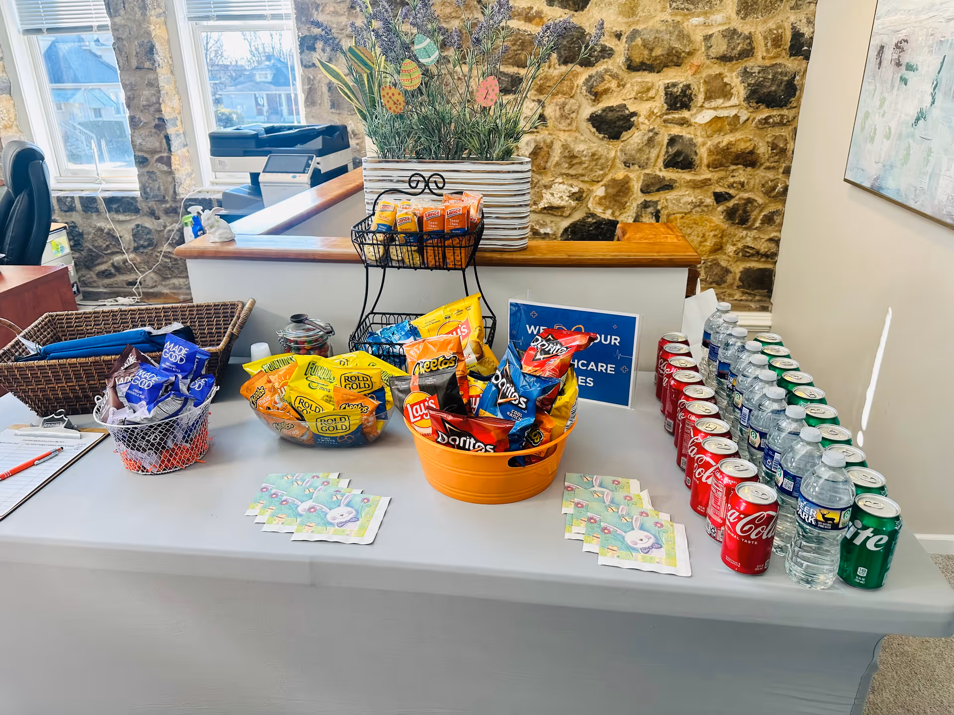 Snack station with chips, soda, and water on a counter inside a stone-walled lobby.