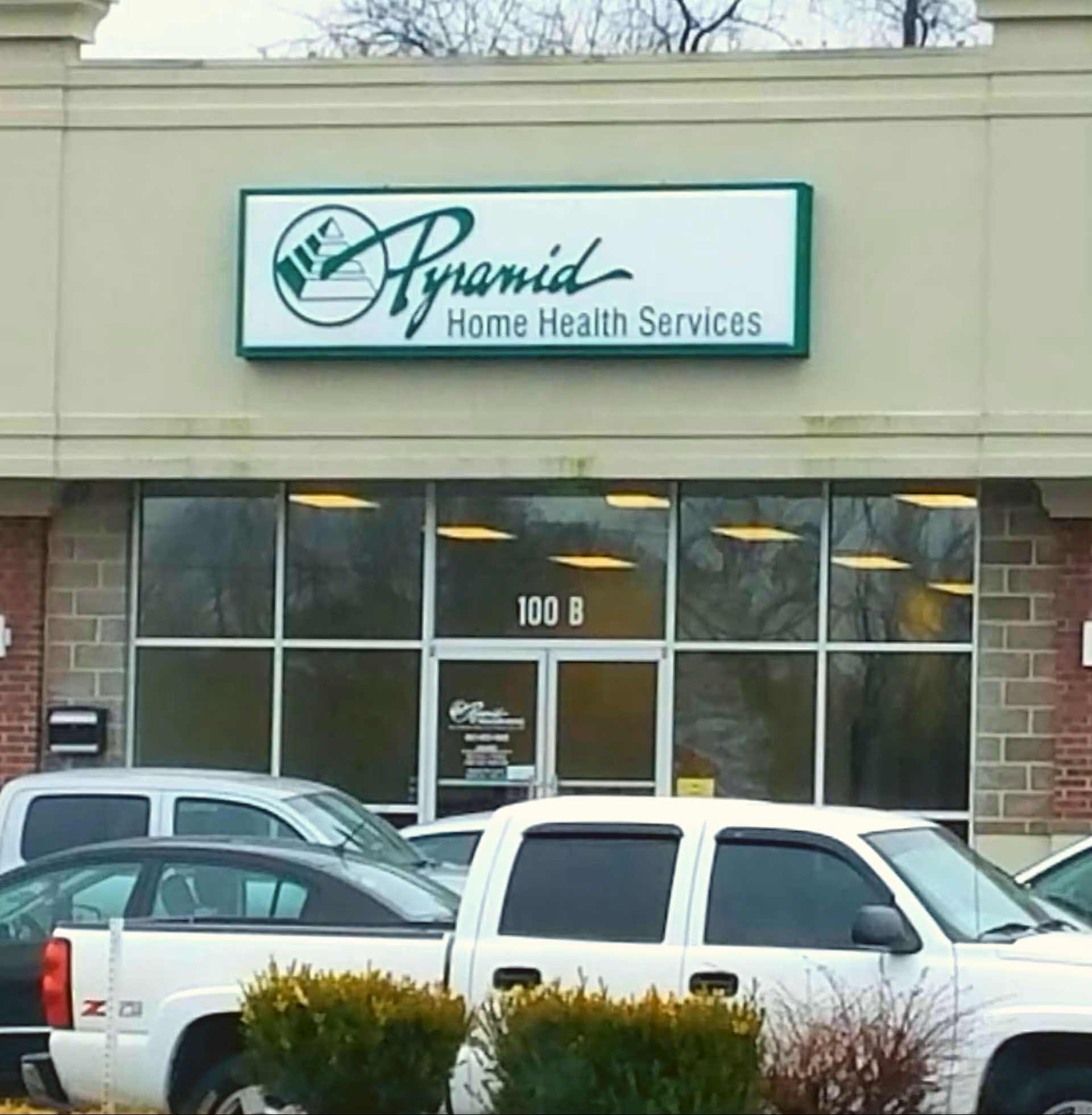 Front view of Pyramid Home Health Services storefront with parked vehicles.