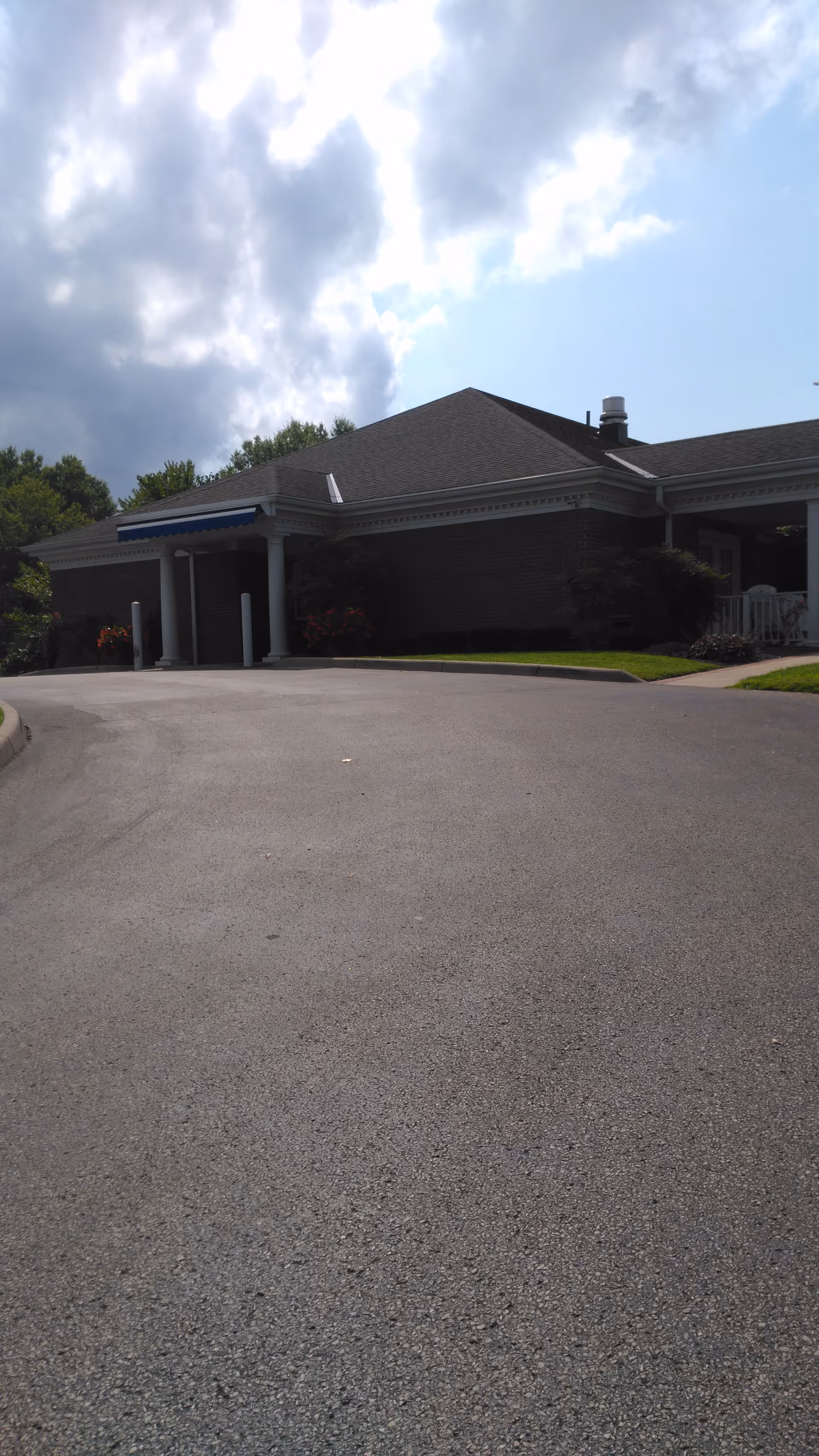 Exterior view of Hospice of Huntington building with driveway, entrance canopies, and surrounding greenery.