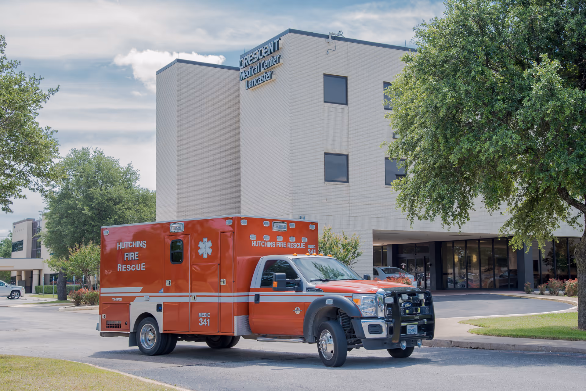 Exterior view of Crescent Regional Hospital with a red Hutchins Fire Rescue ambulance parked in front.