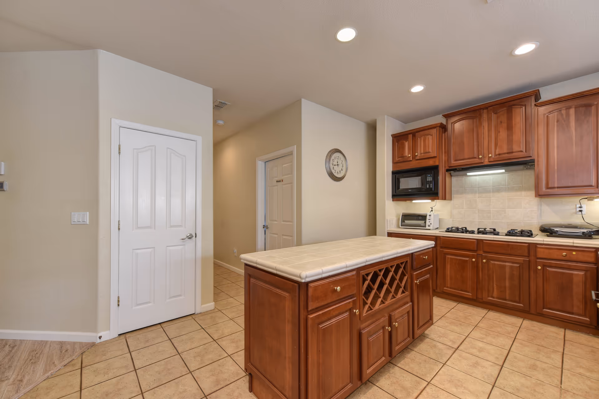 Modern kitchen with wooden cabinets, tiled island, and appliances in a senior living facility.
