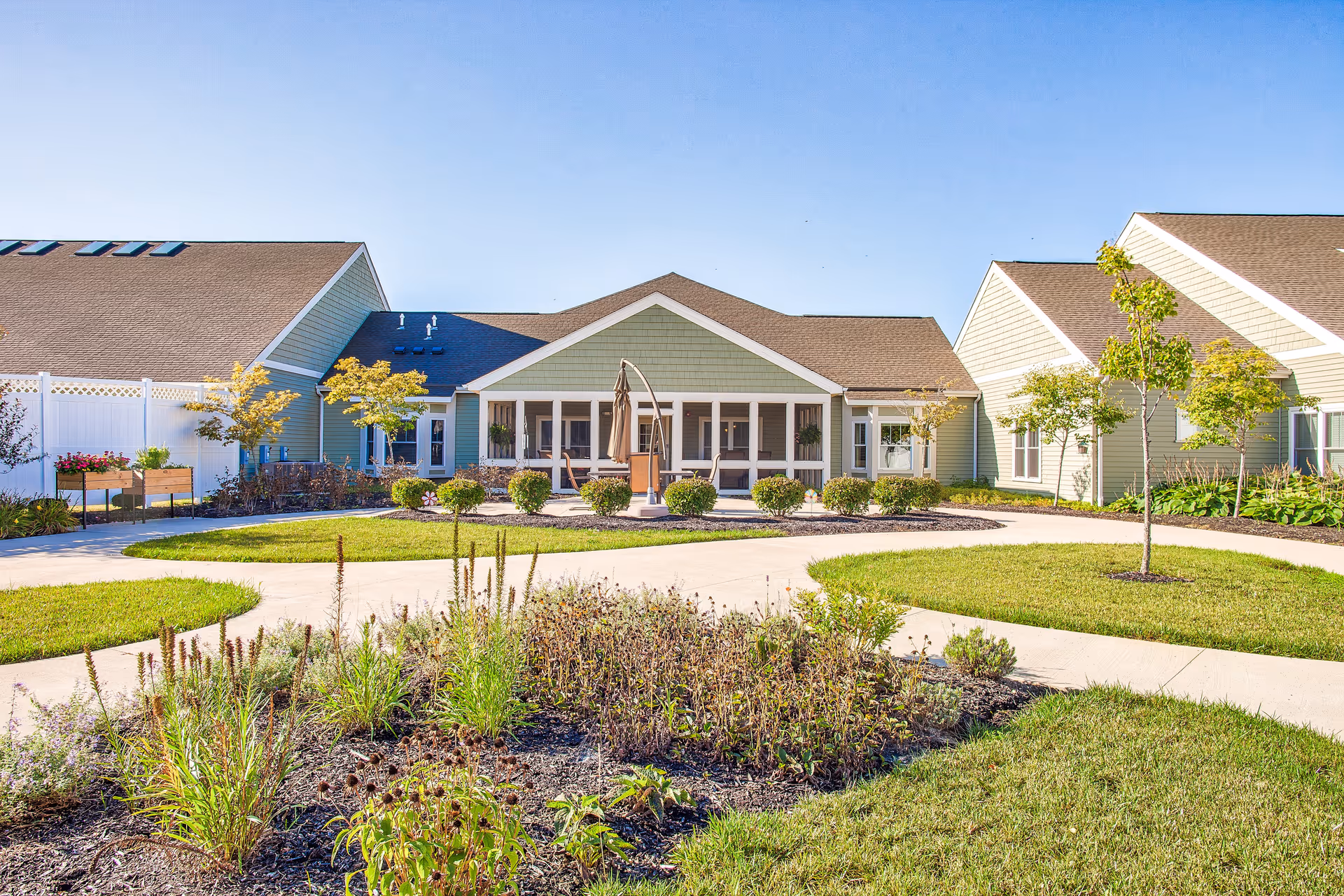 Exterior view of a senior living facility with a central entrance and landscaped grounds.