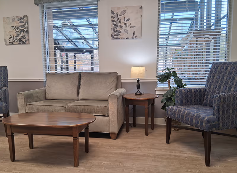 Cozy living room lounge with sofa, armchairs, coffee table, lamp, and plant