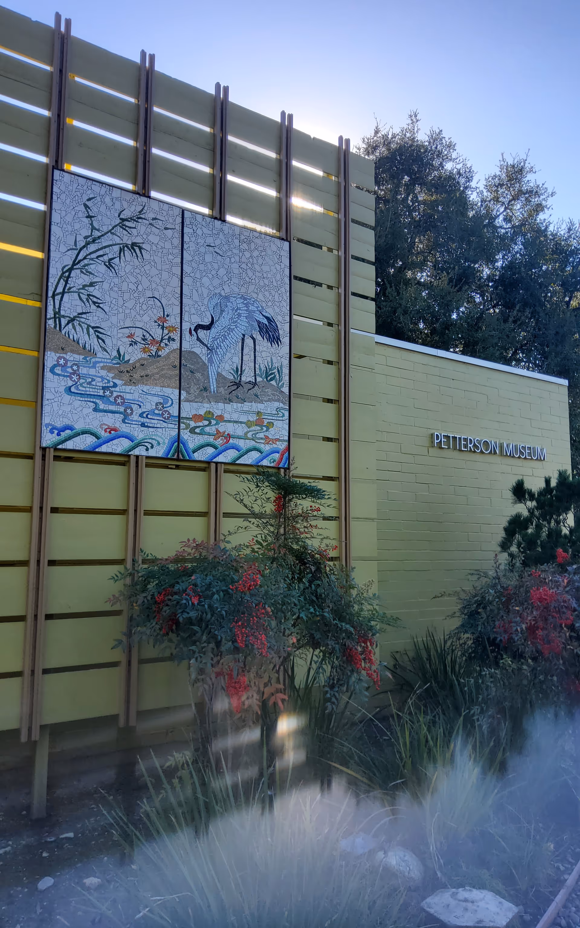 Exterior of a yellow building with a mosaic panel and a Petterson Museum sign.