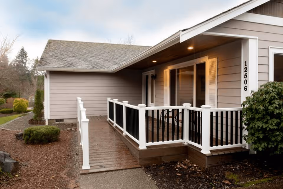Front porch and ramp of a single-story house with white railing, sliding glass door, and house number 12506.