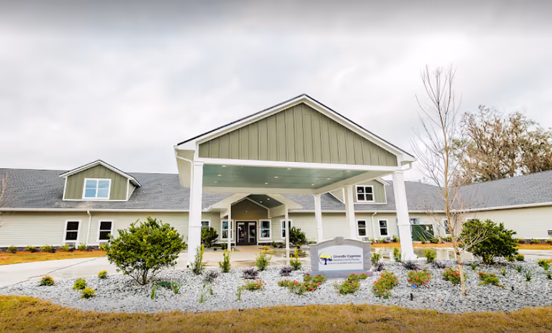 Exterior view of Grande Cypress Assisted Living Facility entrance with landscaping.