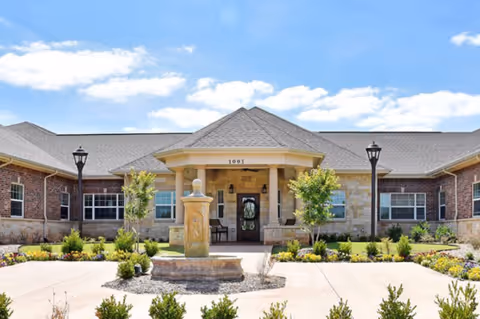 Single-story brick senior care center with a covered entrance and landscaped front yard.