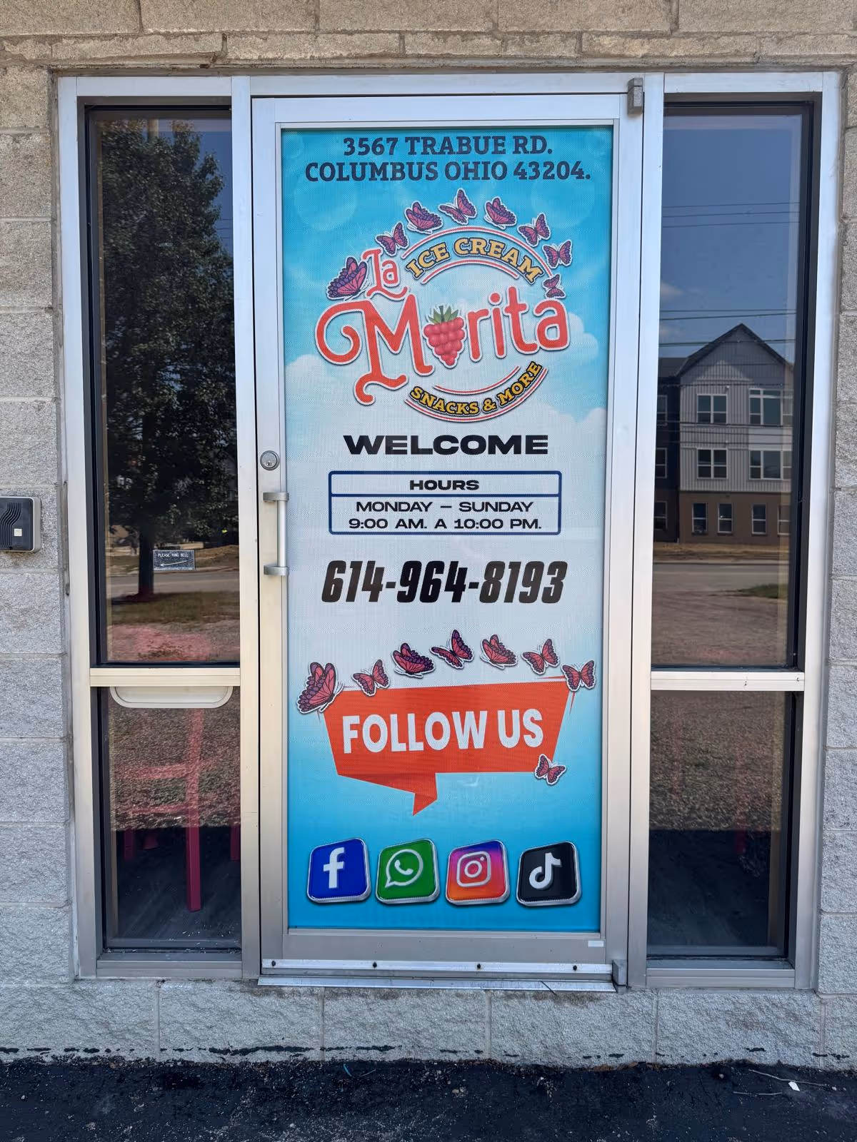 A glass door with a bright vertical poster for Morita ice cream and social media