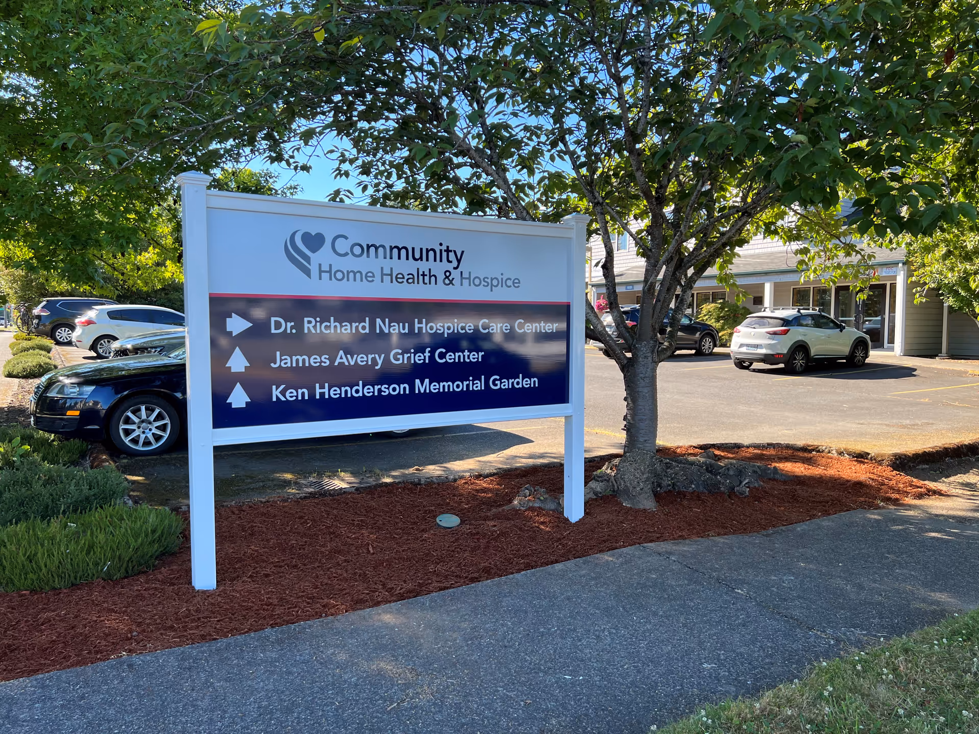 Outdoor sign for Community Home Health & Hospice with arrows and a building behind.