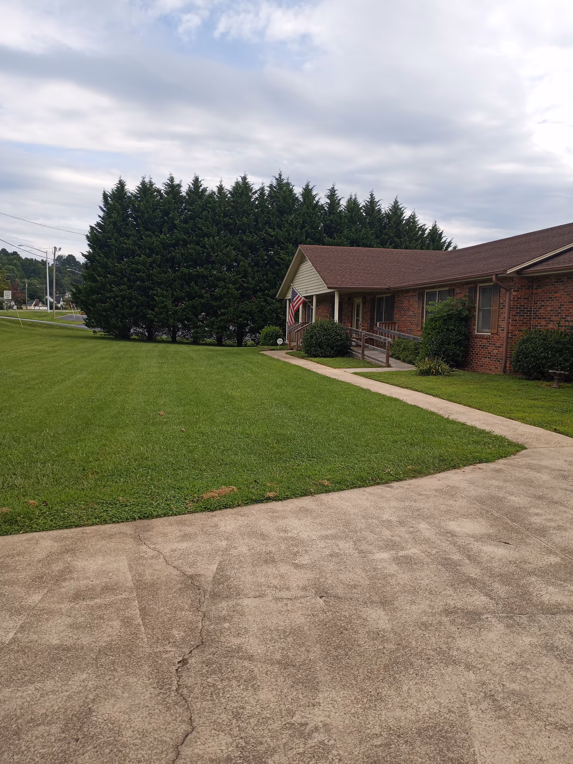 Front exterior of TLC Family Care Home, LLC, brick building with green lawn and walkway.