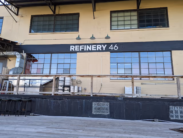 Exterior view of a beige industrial building with large windows and a Refinery 46 sign.