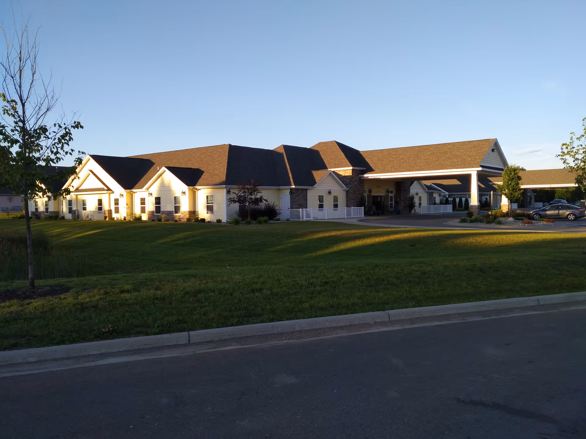 Exterior view of Vicinia Gardens AL senior living facility with manicured lawn and driveway.