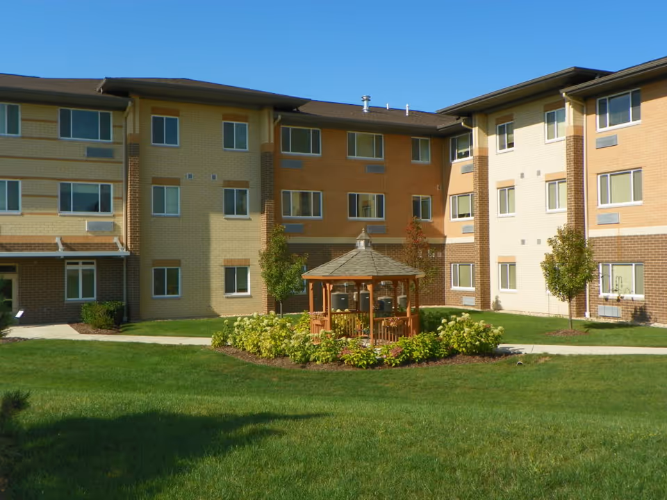 Exterior view of a multi-story senior living building with a central gazebo and courtyard.