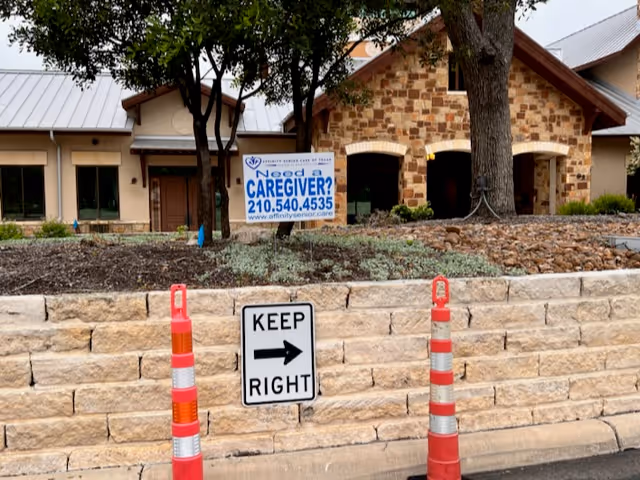 Exterior view of Affinity Senior Care of Texas facility with signs, stone wall, and traffic cones.