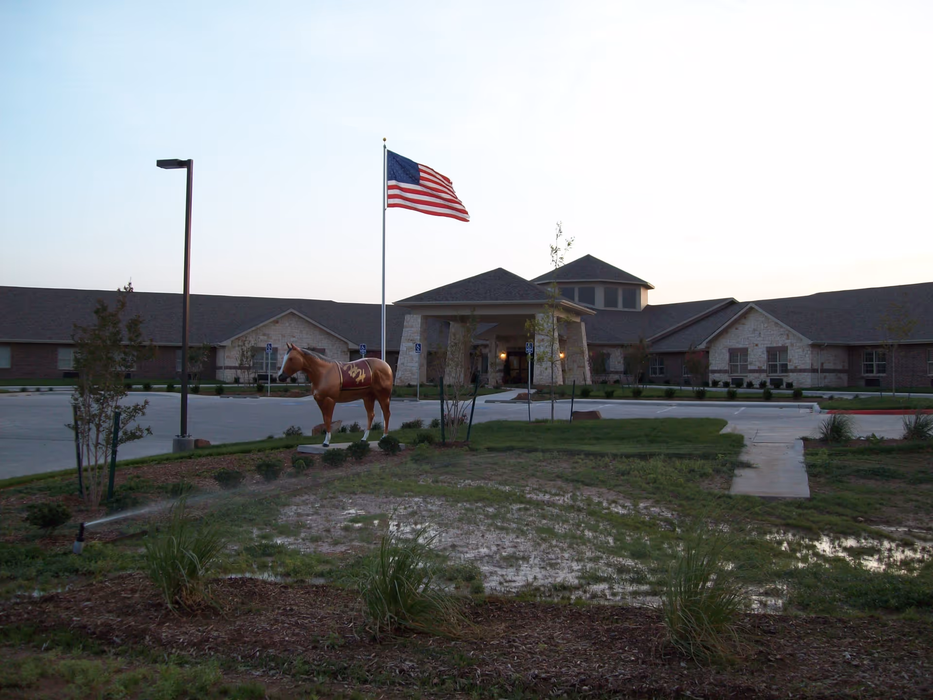 Exterior view of Hillside Heights Rehabilitation Suites with flag, statue, and entrance.