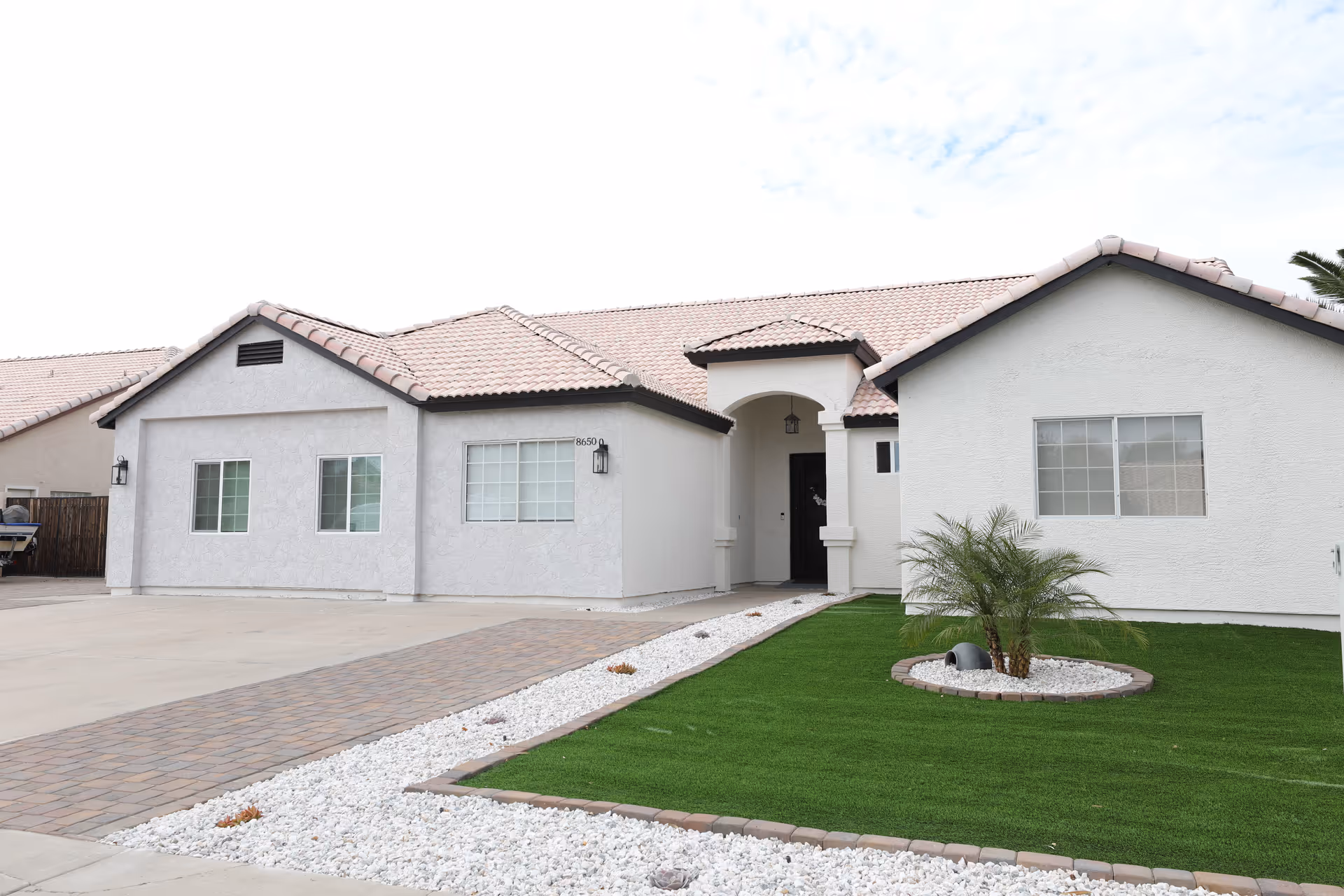 Front view of Bright Oasis Assisted Living: white single-story building with a tiled roof and landscaping.
