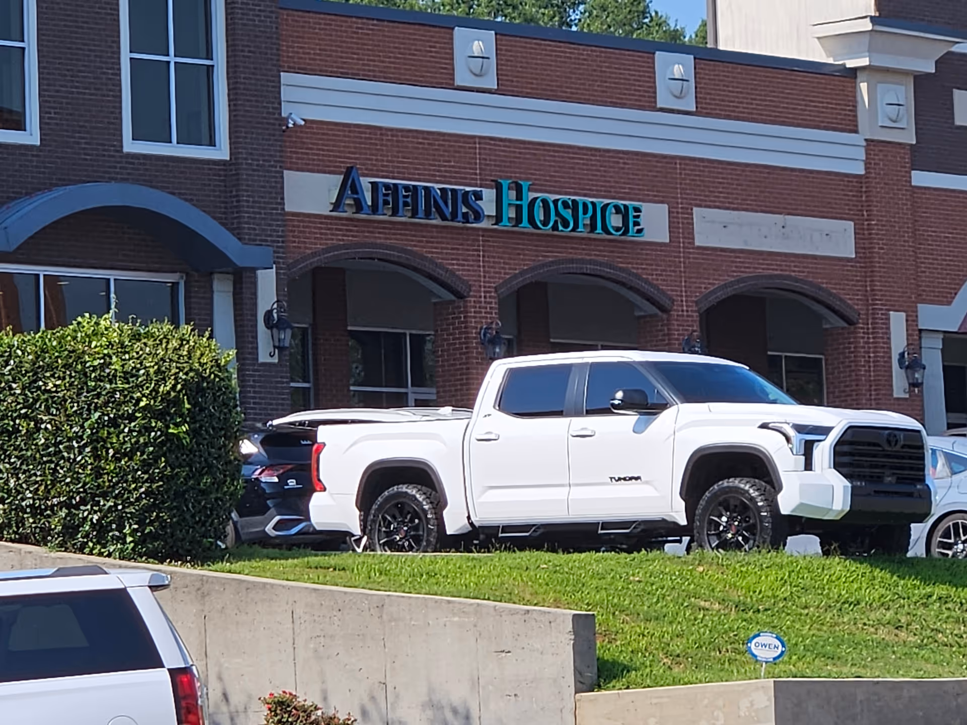 Exterior view of Affinis Hospice building with white pickup trucks parked in front.
