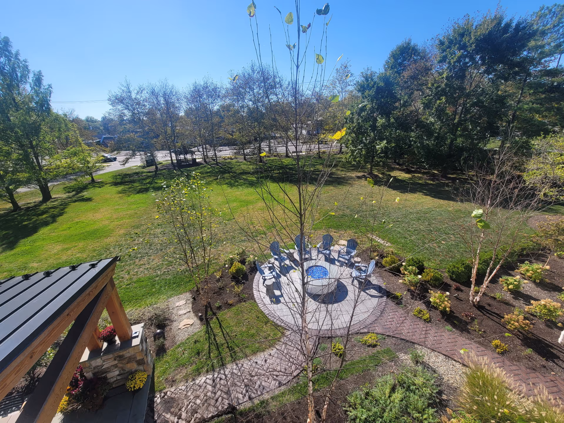 An outdoor courtyard featuring a circular patio with blue chairs surrounding a central table.