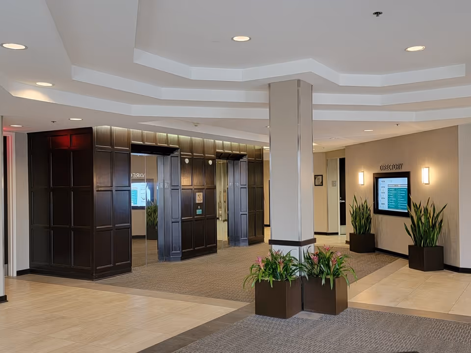 Modern lobby of a senior living facility with a directory screen and potted plants.