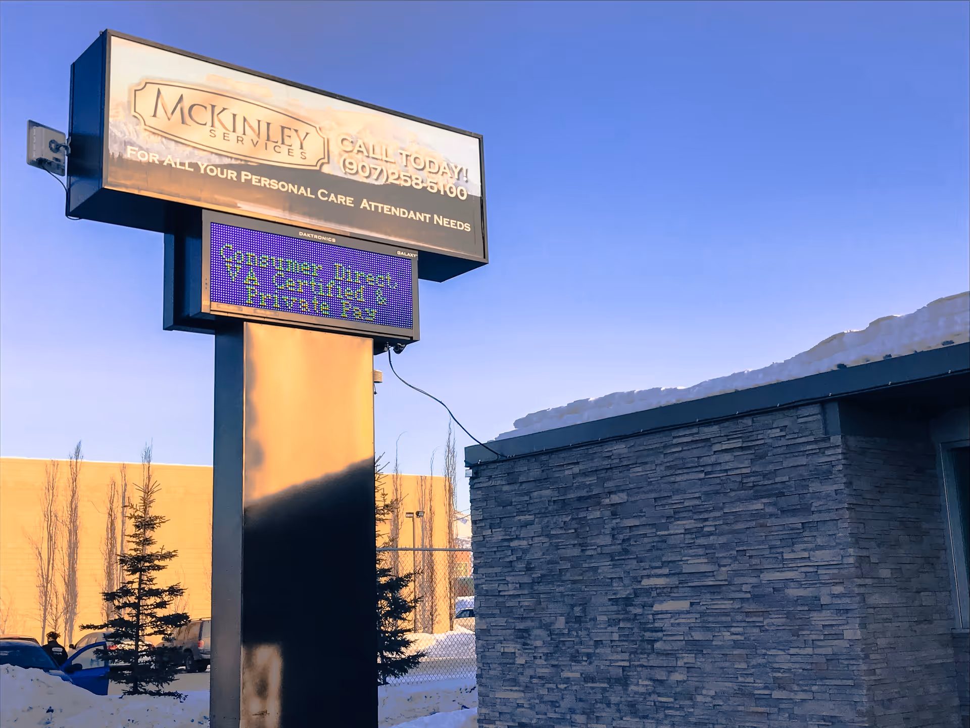 A tall McKinley Services sign with a digital board beside a stone building exterior.