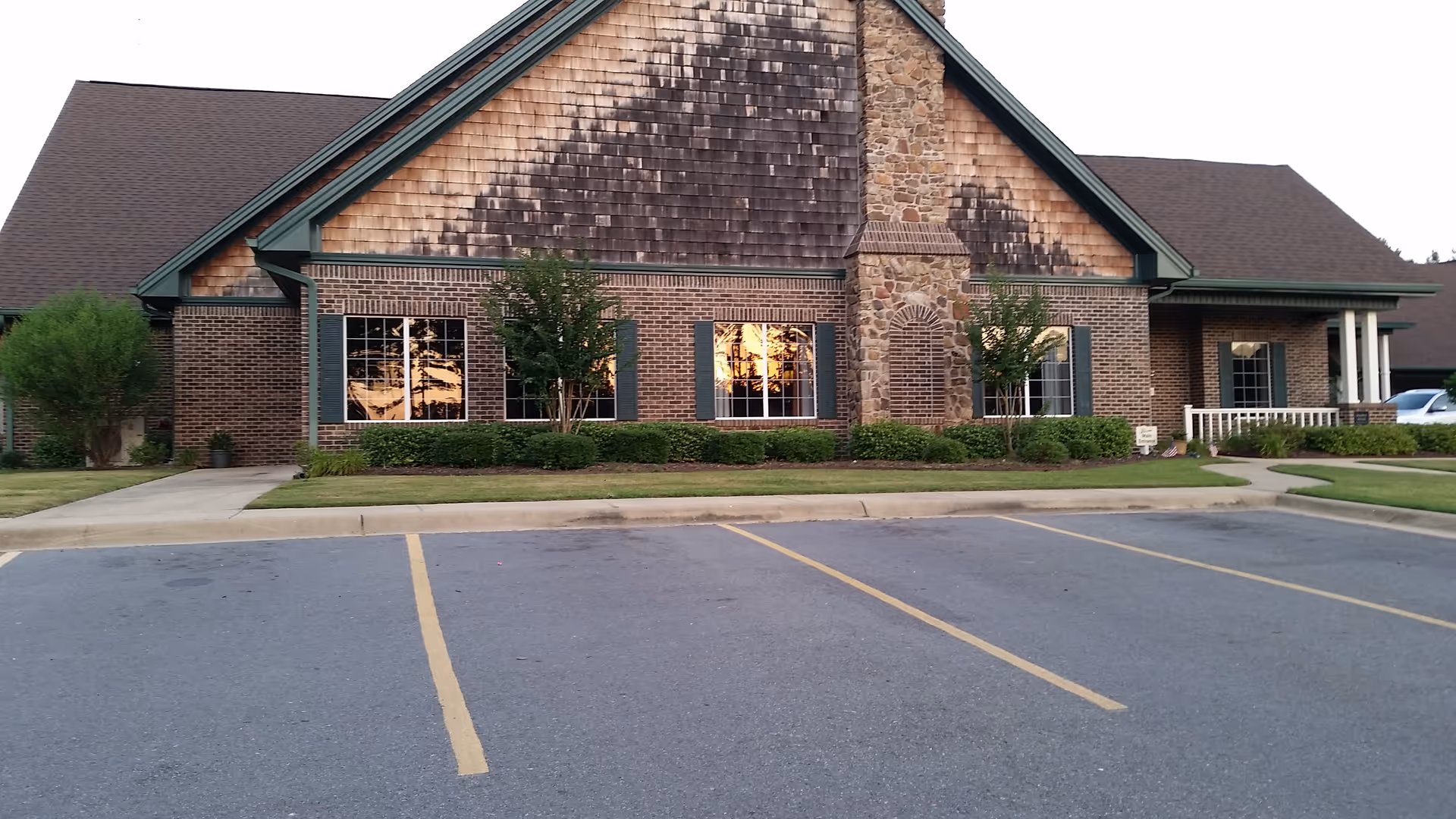 Front view of a brick hospice building with windows and parking lot.