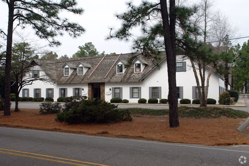 Exterior of Aegis Home Care building with white walls and trees.