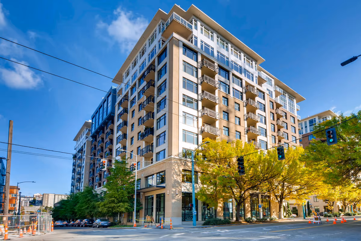 Exterior view of Mirabella Seattle, tall modern senior living building with street and trees.