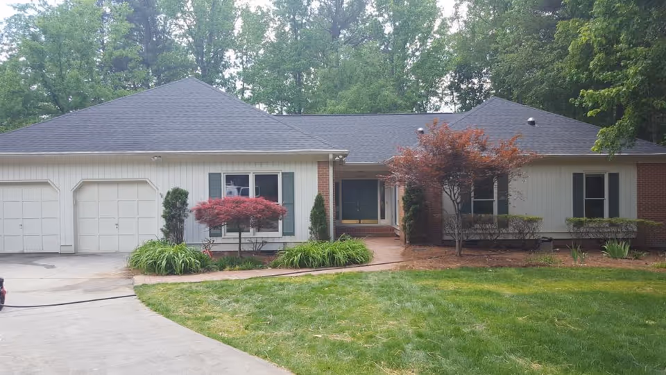 Front exterior of a single-story ranch-style house with an attached two-car garage, driveway, front lawn, and landscaping.