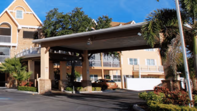 Exterior view of Bayside Terrace senior living with a covered entrance and parked cars.