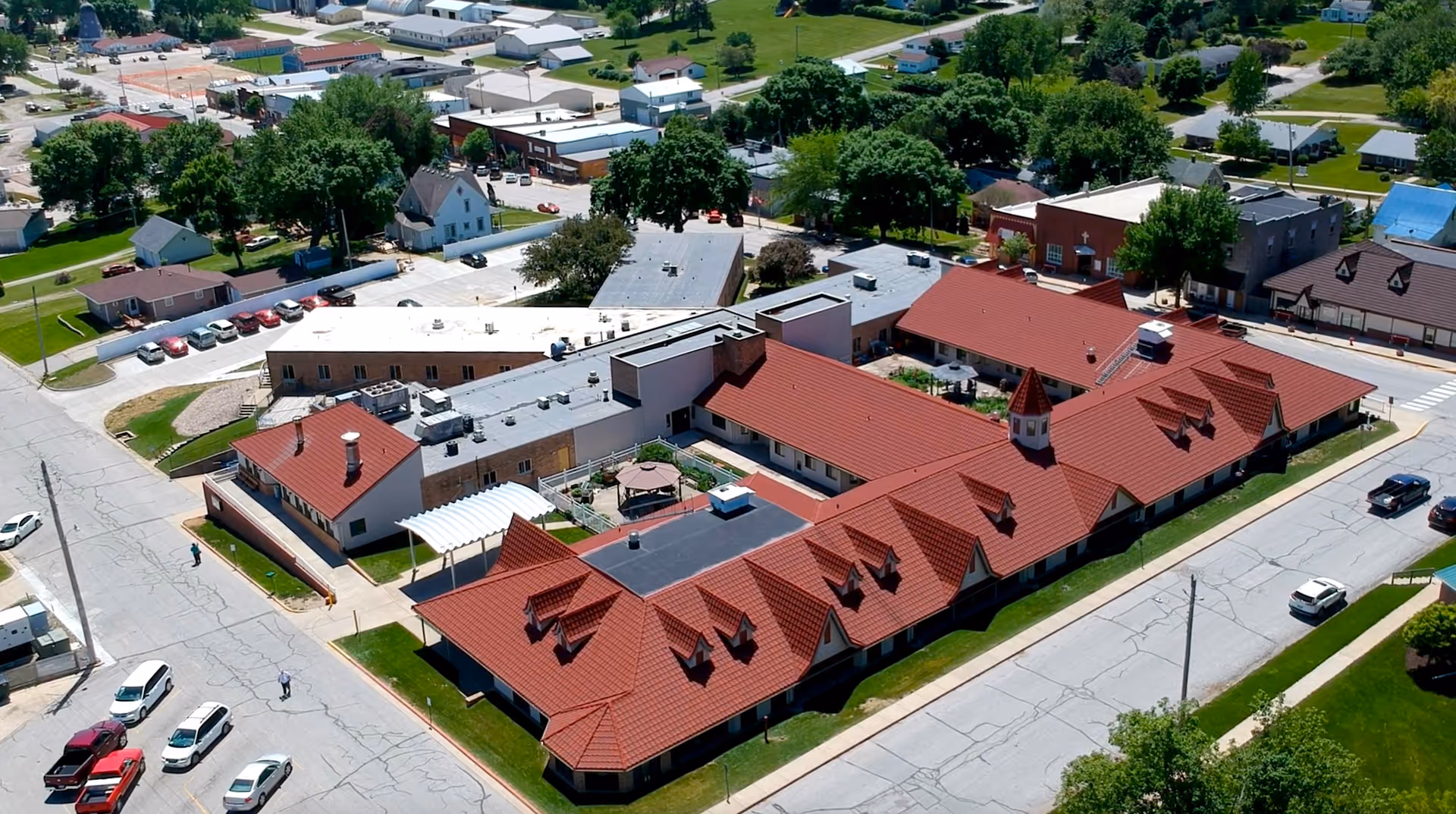 Aerial view of Salem Lutheran Homes and Rehabilitation Center showing a large building complex with red roofs, surrounded by streets, parked cars, and greenery in a small town setting.