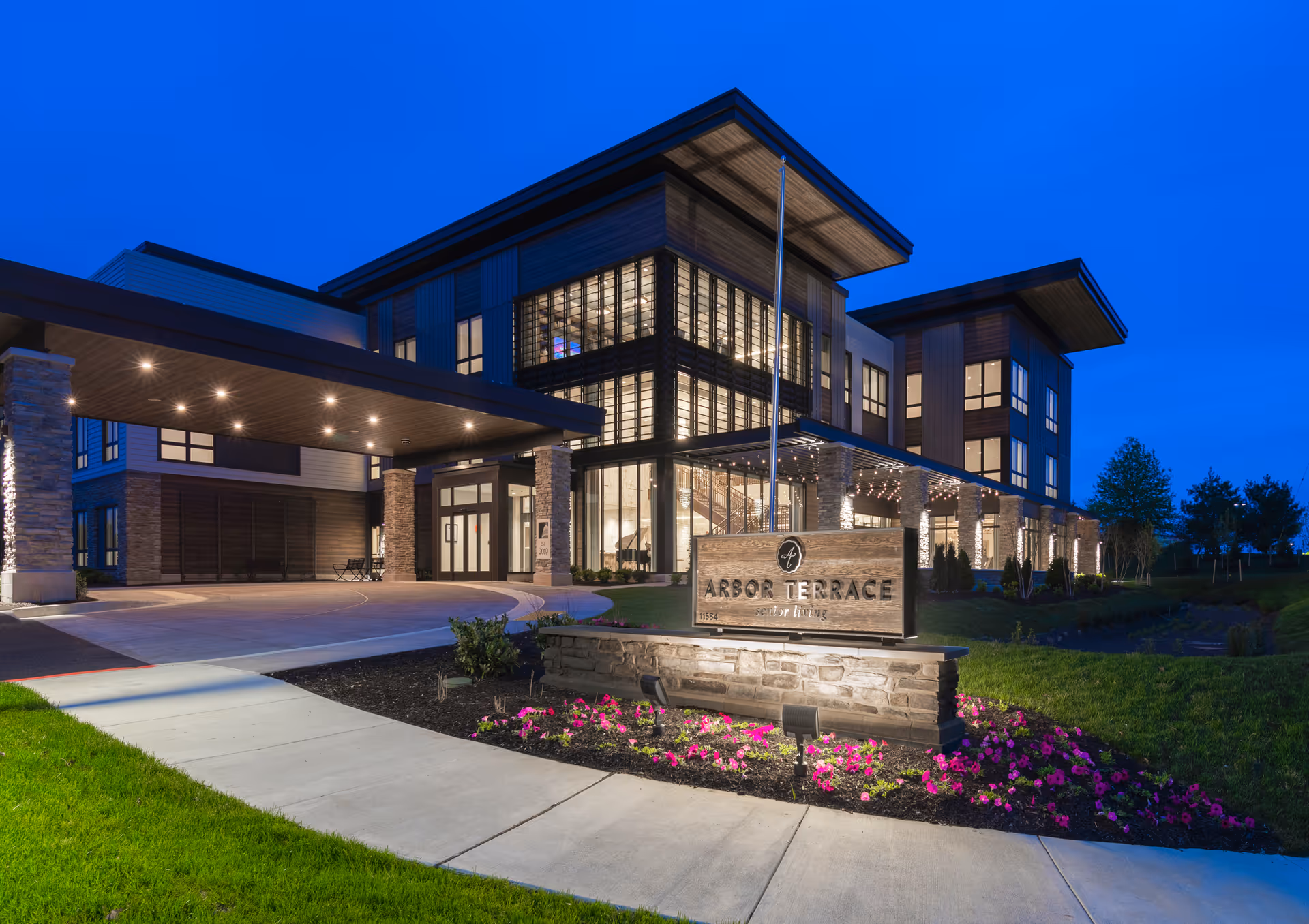 Modern senior living facility exterior at dusk with illuminated Arbor Terrace sign and entry canopy.