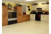 Interior kitchen area with wooden cabinets, white appliances, and a TV stand.