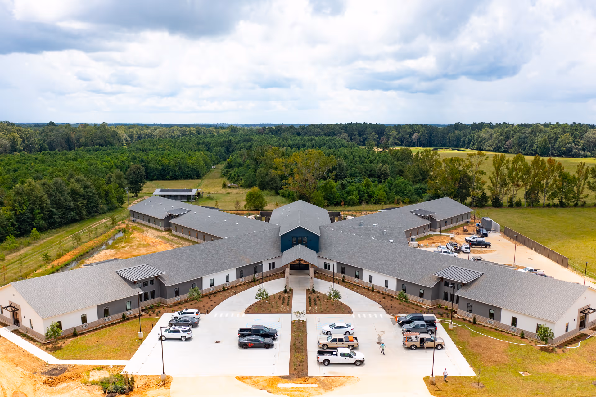 Aerial view of a large L-shaped nursing center with parking and trees.