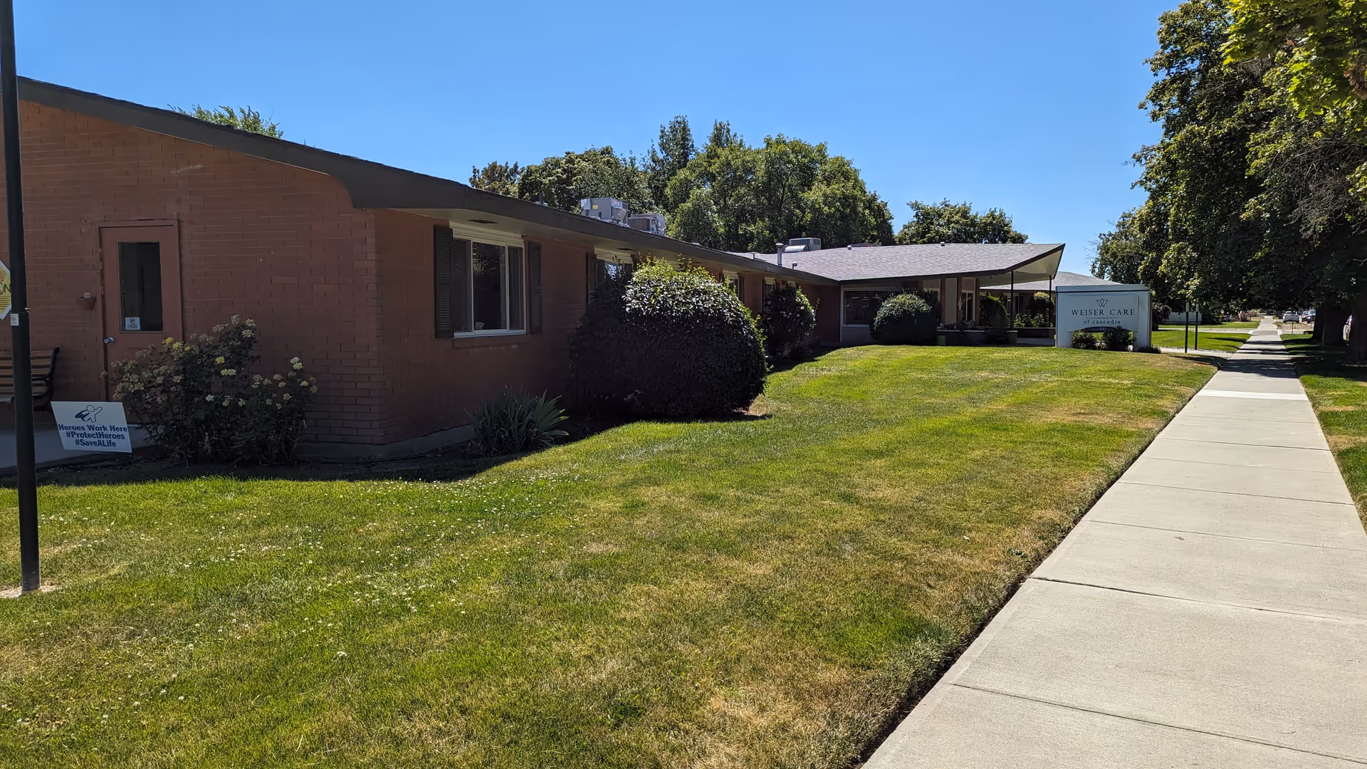 A single-story brick senior living facility, Weiser of Cascadia, with manicured lawn and walkway.