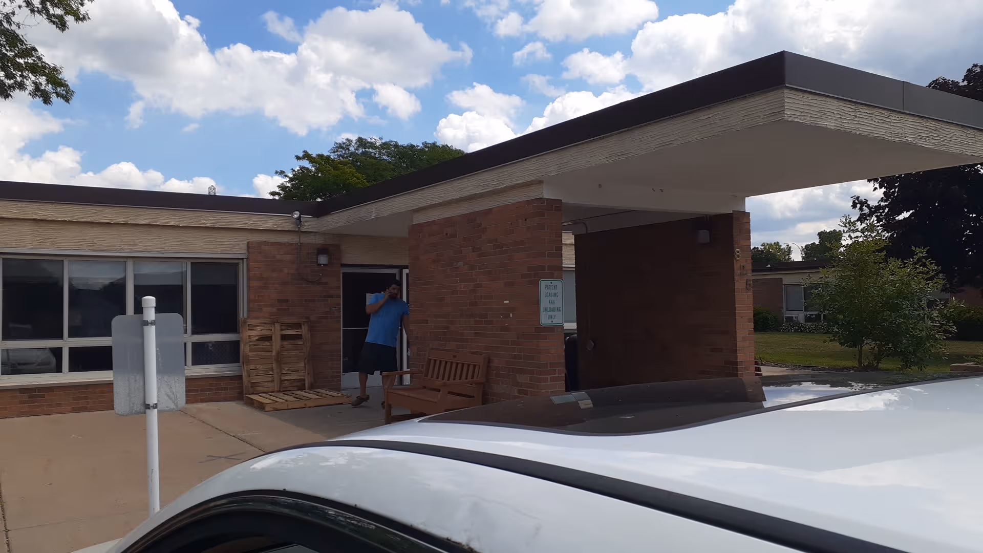 Front entrance of a brick senior living facility with a car in the foreground.