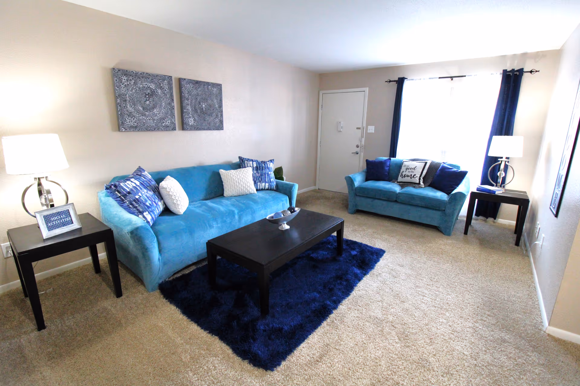 Two blue couches surround a dark coffee table in a bright living room.