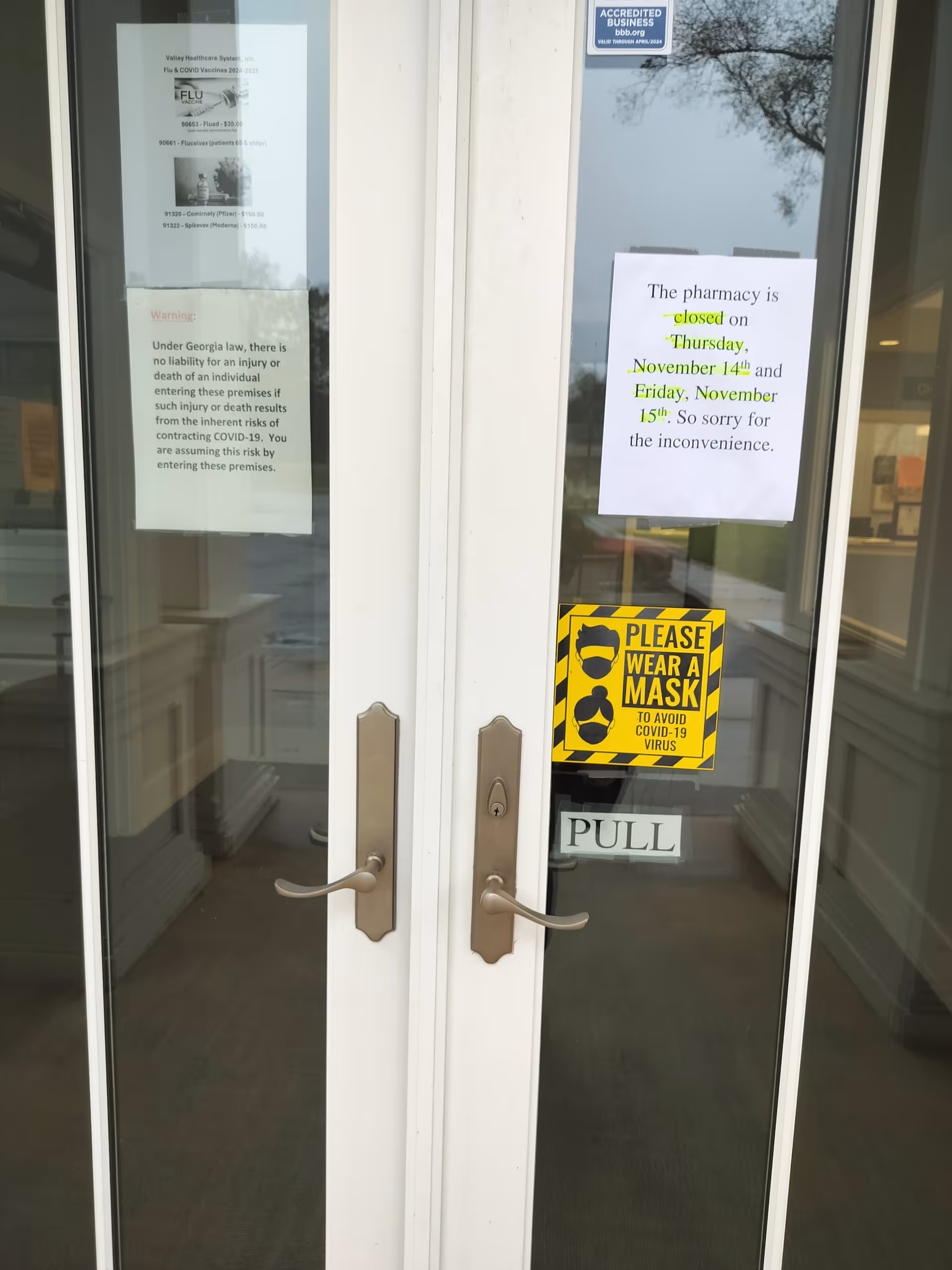 Front glass doors with posted notices, a mask sign, and a pull handle.