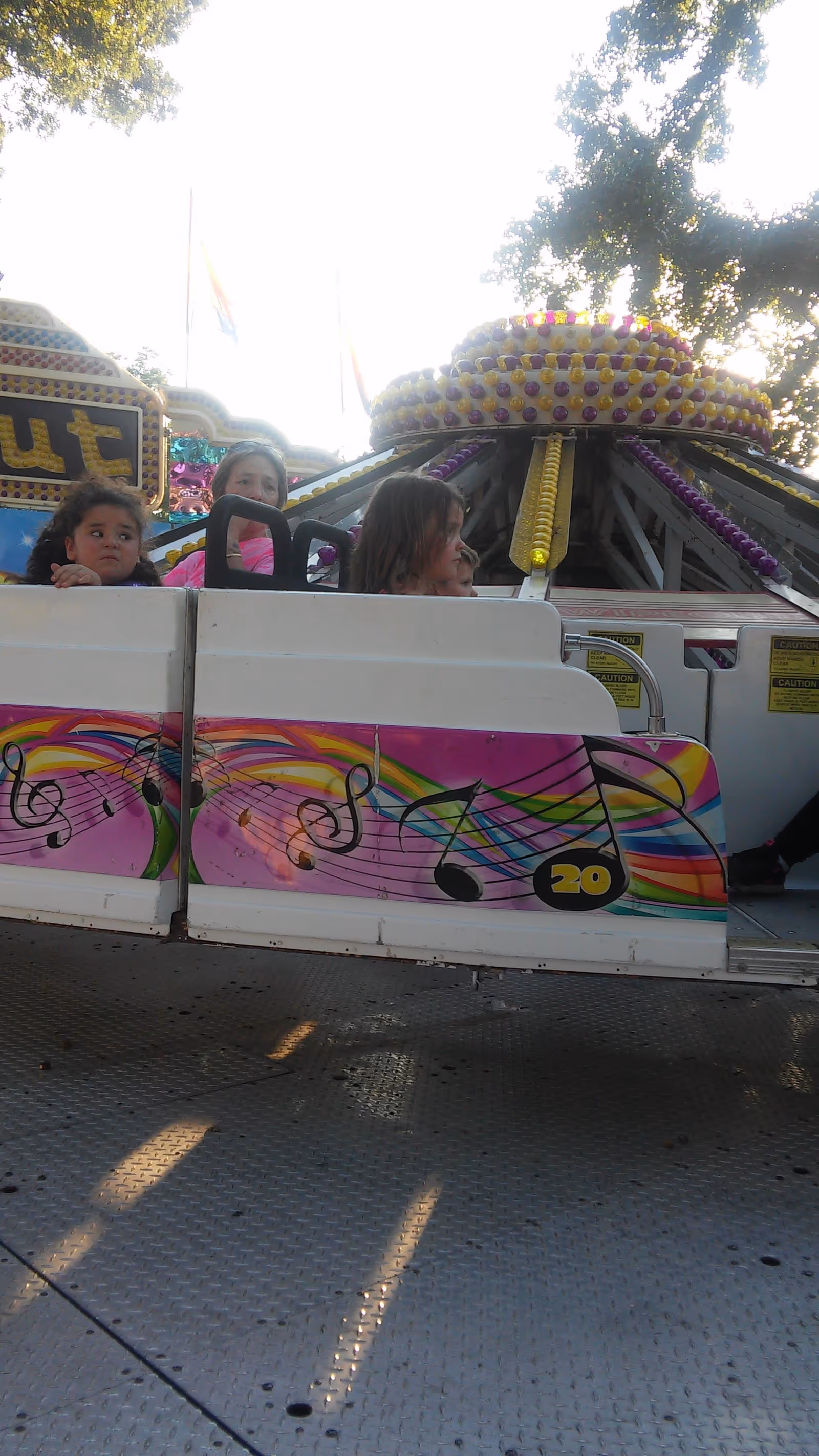 Children ride a colorful carnival ride outdoors.