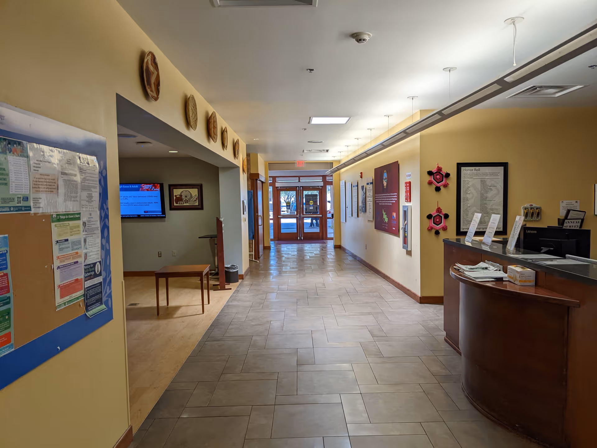 Long hallway inside a senior living center with a reception desk and bulletin boards.