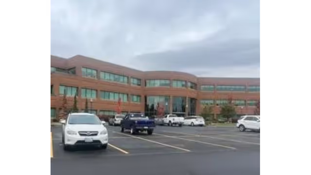 Red brick building with a glass entrance and surrounding parking lot.