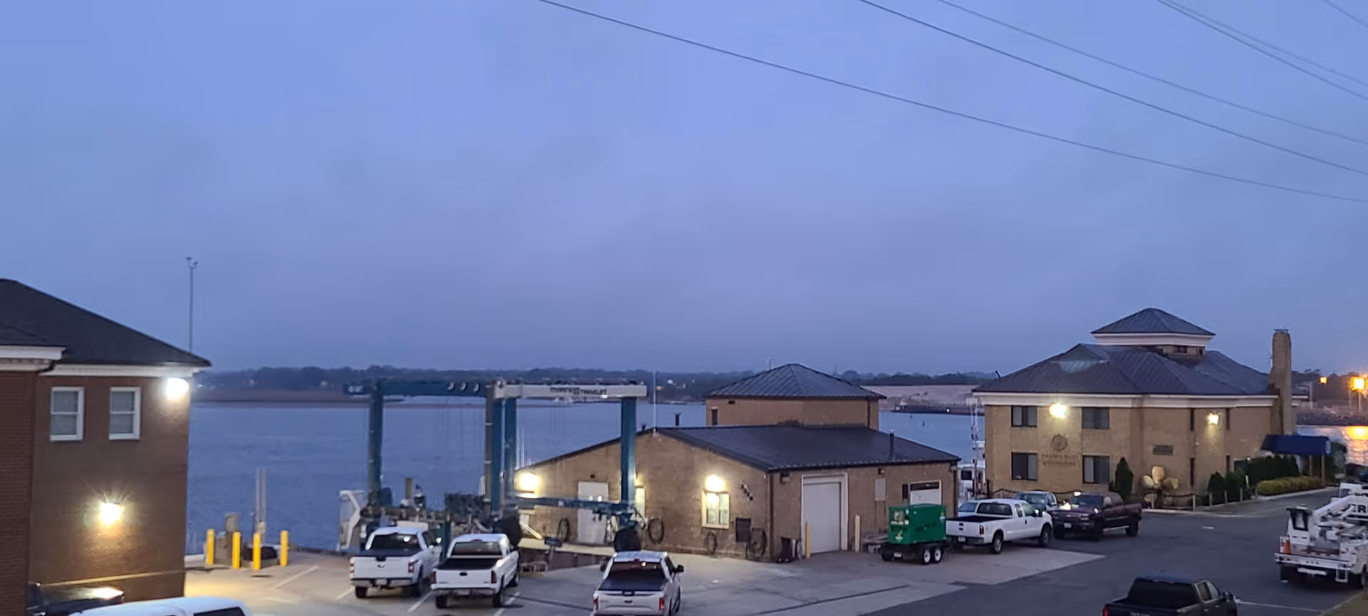 Evening view of a waterfront senior living campus with brick buildings and parked cars.