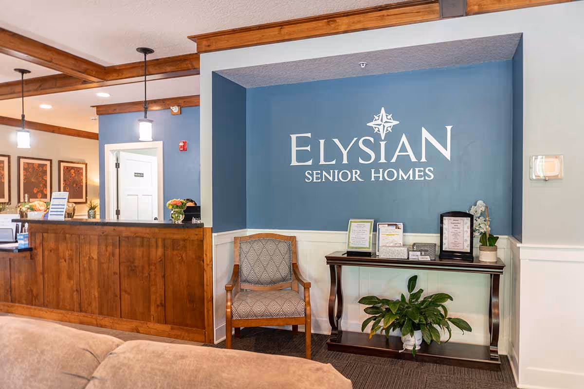 Reception area of Elysian Senior Homes featuring a blue logo wall and seating.