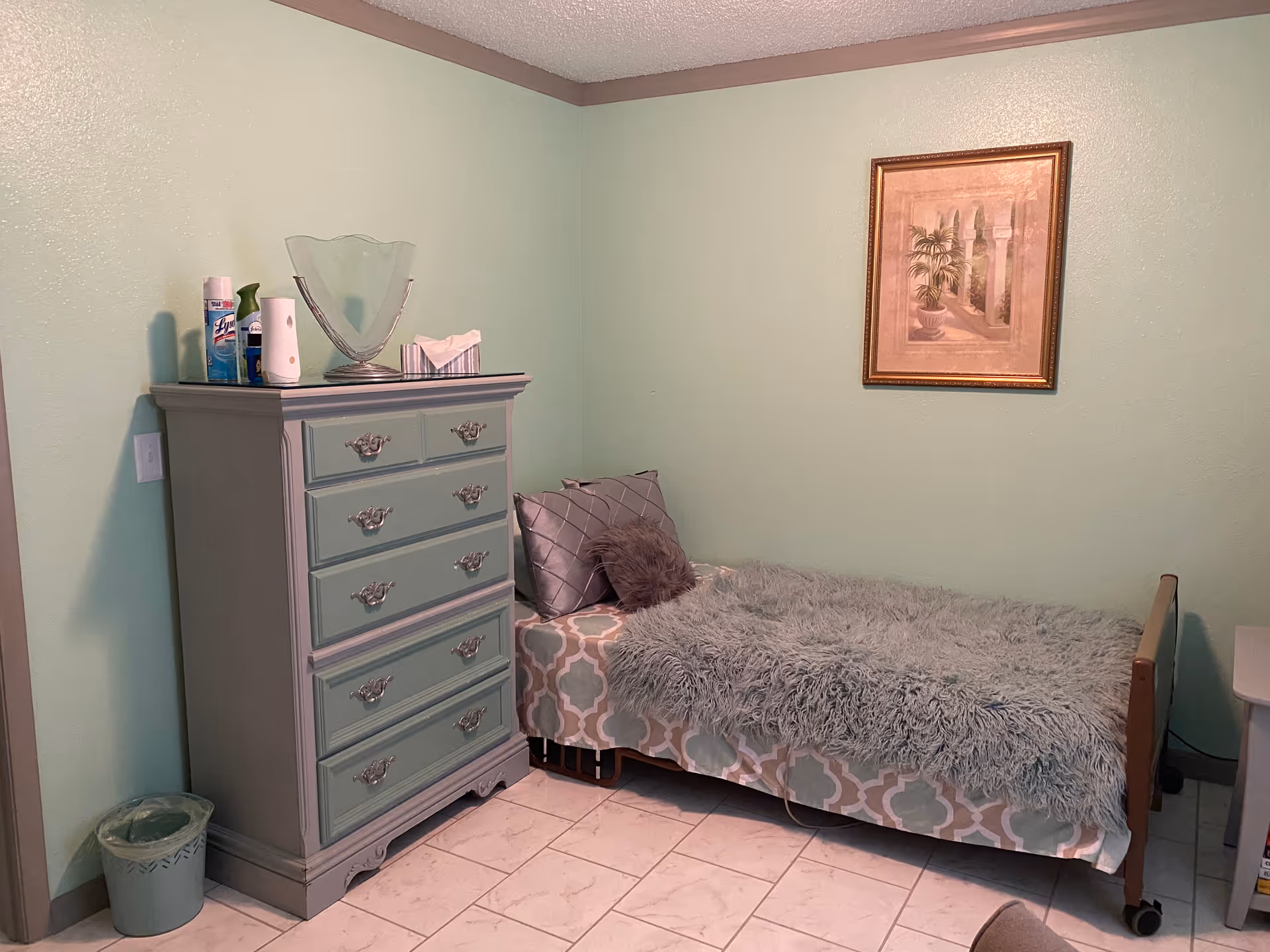 Mint-green bedroom with a single bed, dresser, and wall art.