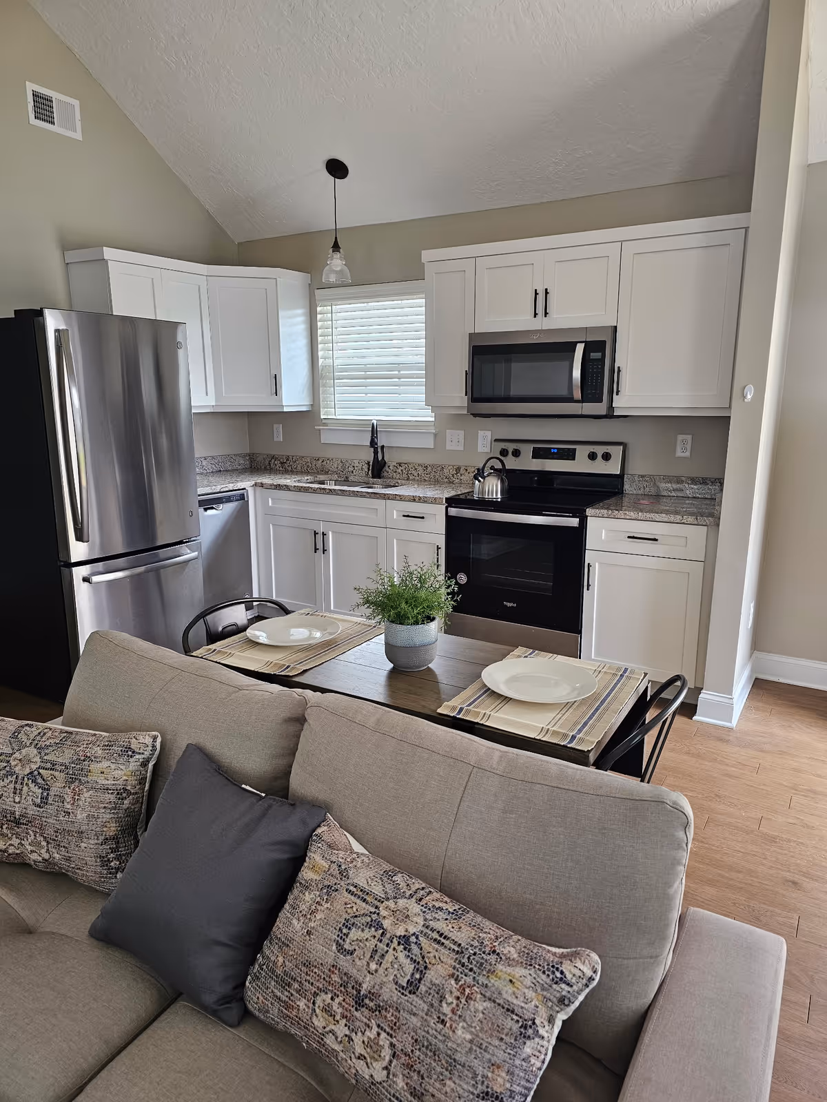 Open-concept living area with a sofa, dining table, and modern kitchen in the background.