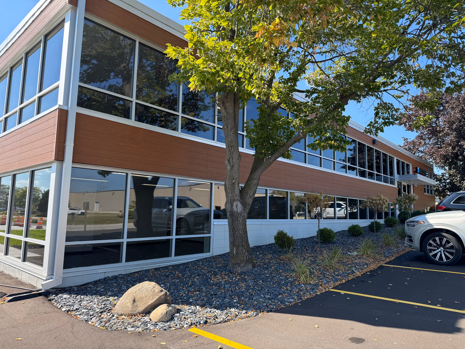 Two-story CarePatrol building with expansive glass windows, tree, and surrounding parking lot.