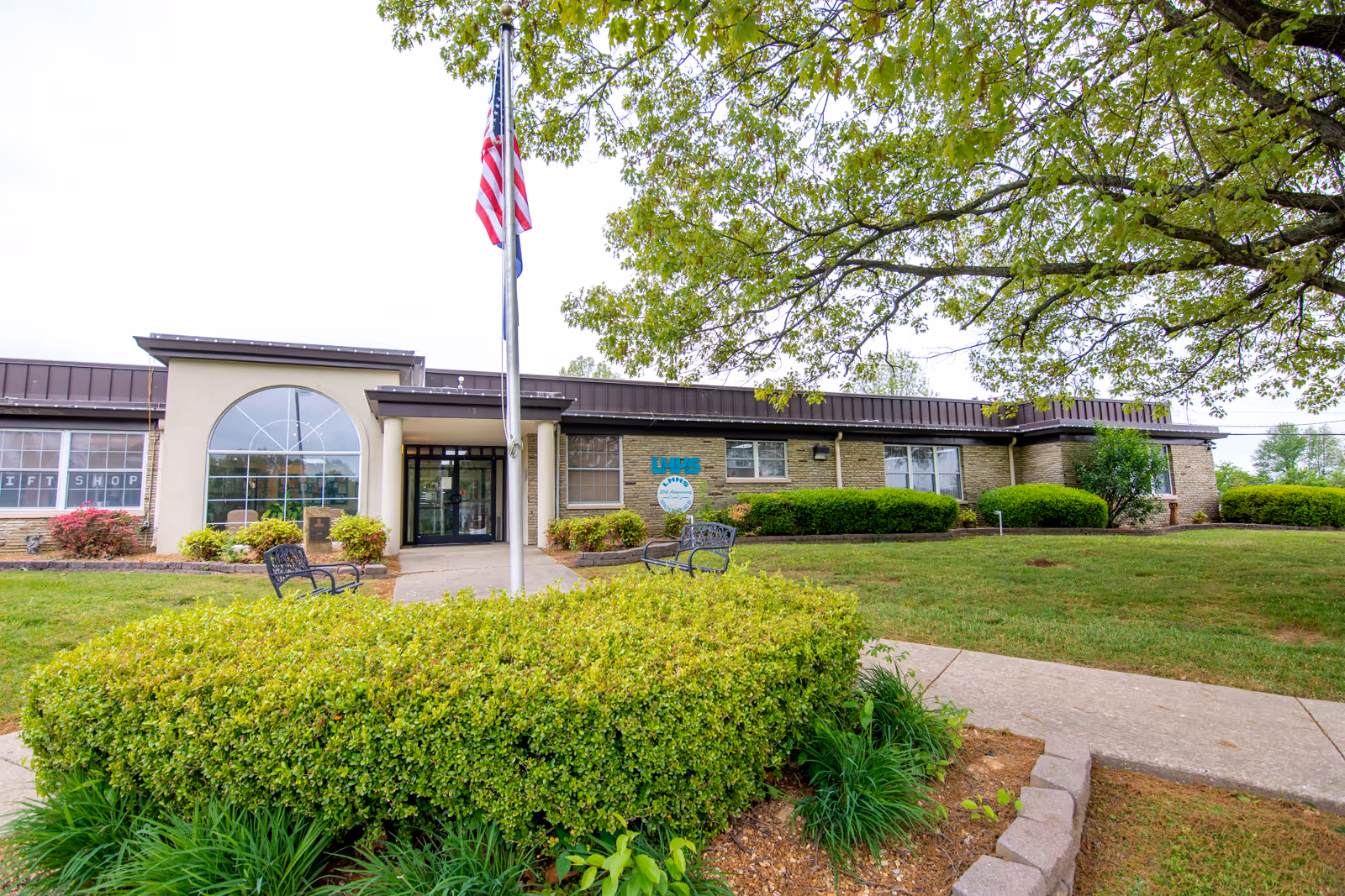 Front view of Livingston Hospital entrance with flagpole and benches on neatly landscaped grounds.