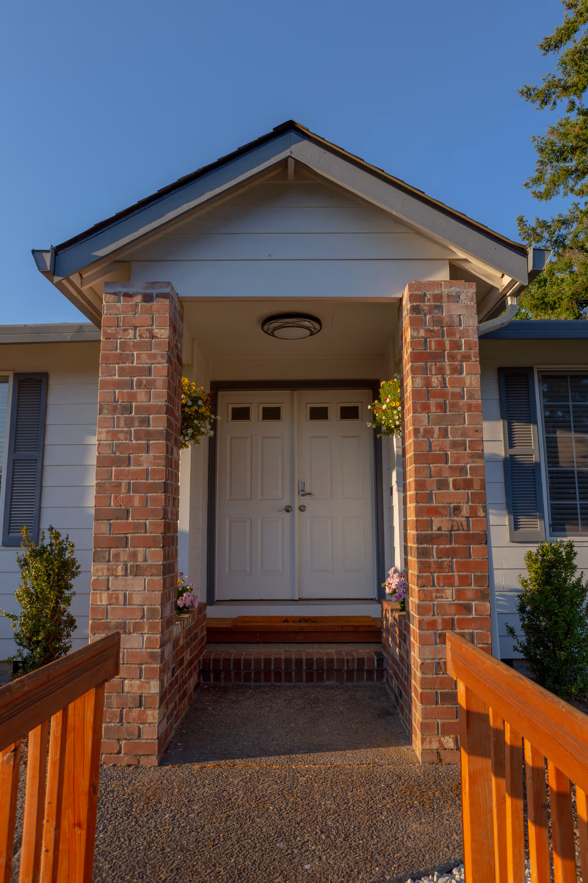 Front entrance of a senior living building with brick columns and a wooden ramp.